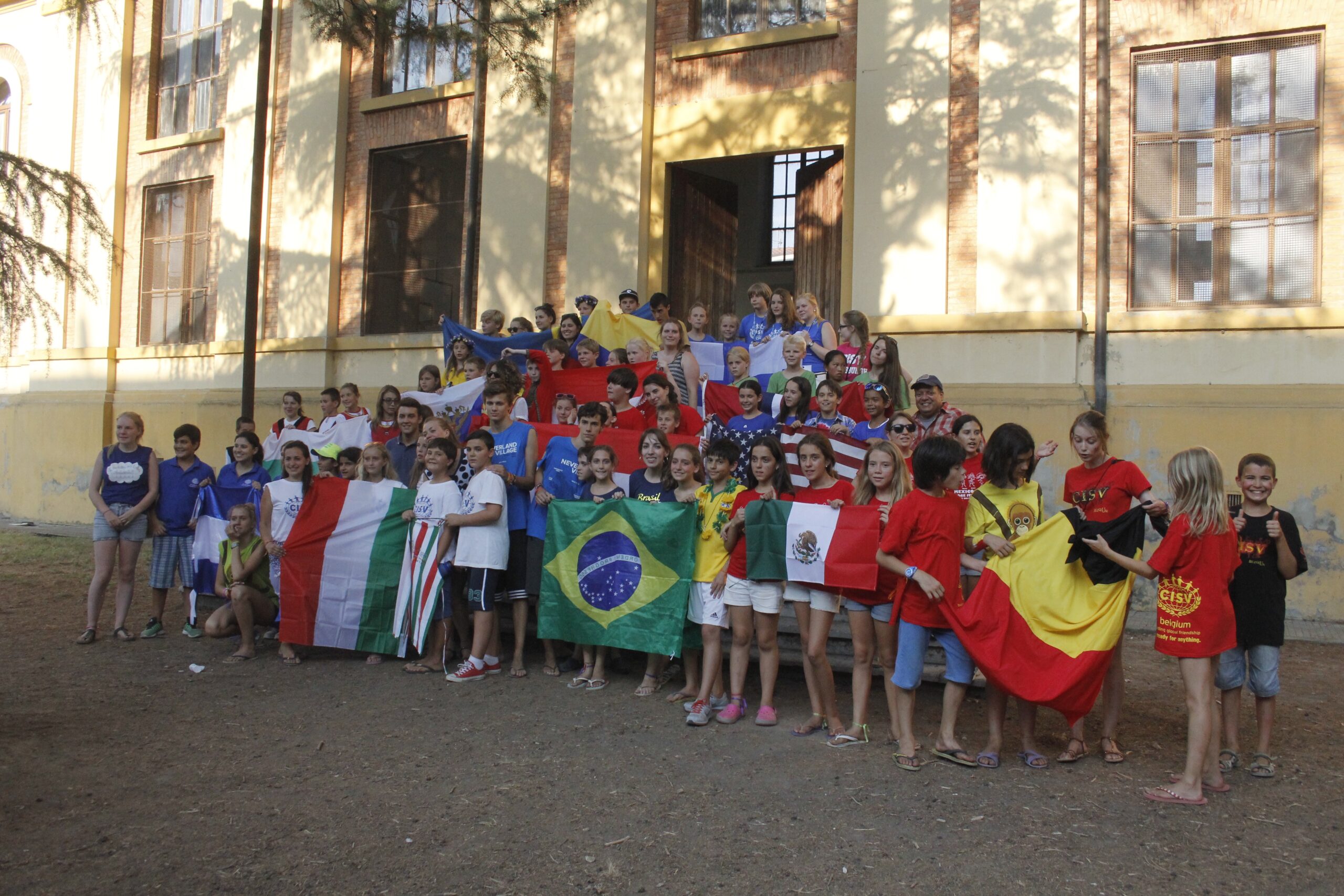 Picture of campers at village in Italy holding flags representing many countries